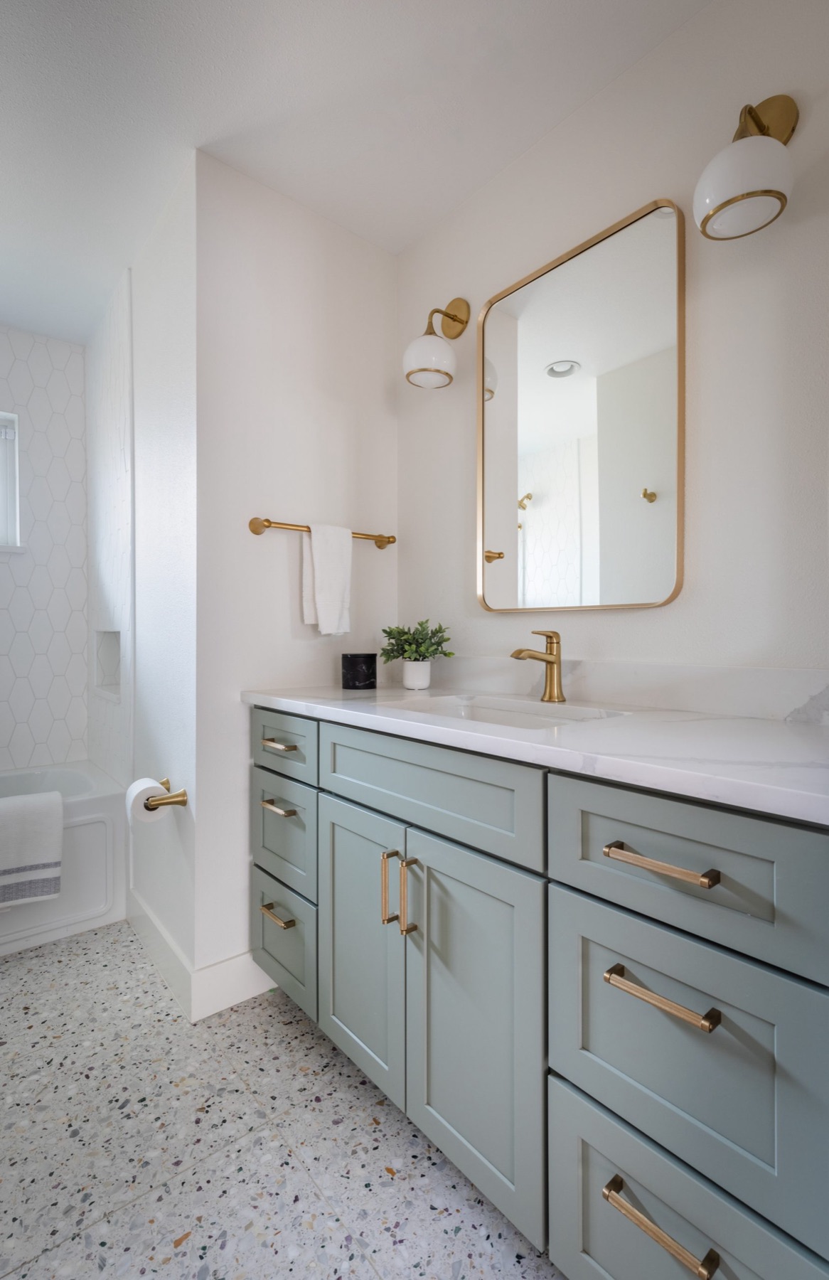 Bathroom vanity with sage green cabinetry and brass fixtures