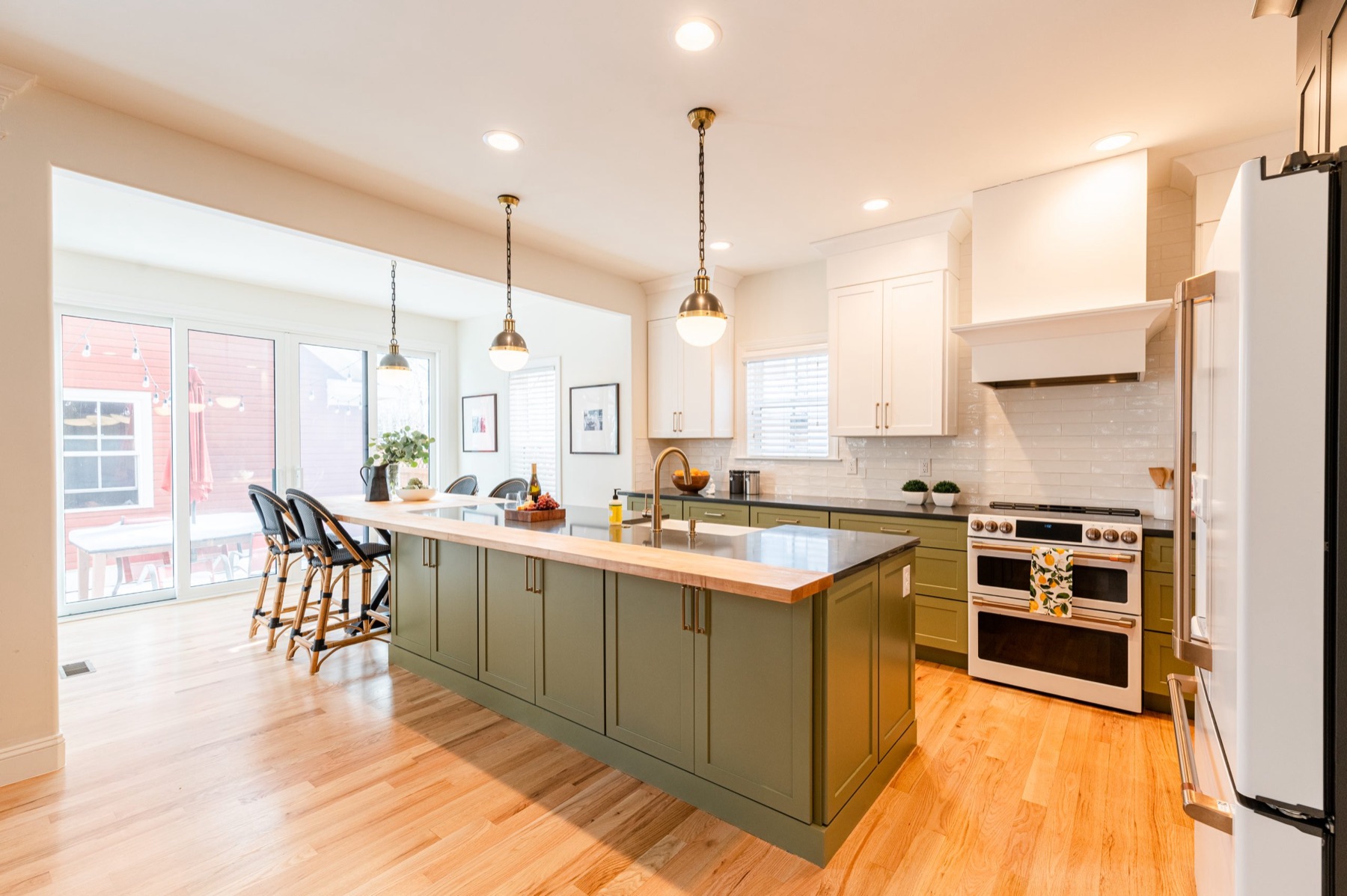 Remodeled kitchen with an olive green island and brass pendant lights