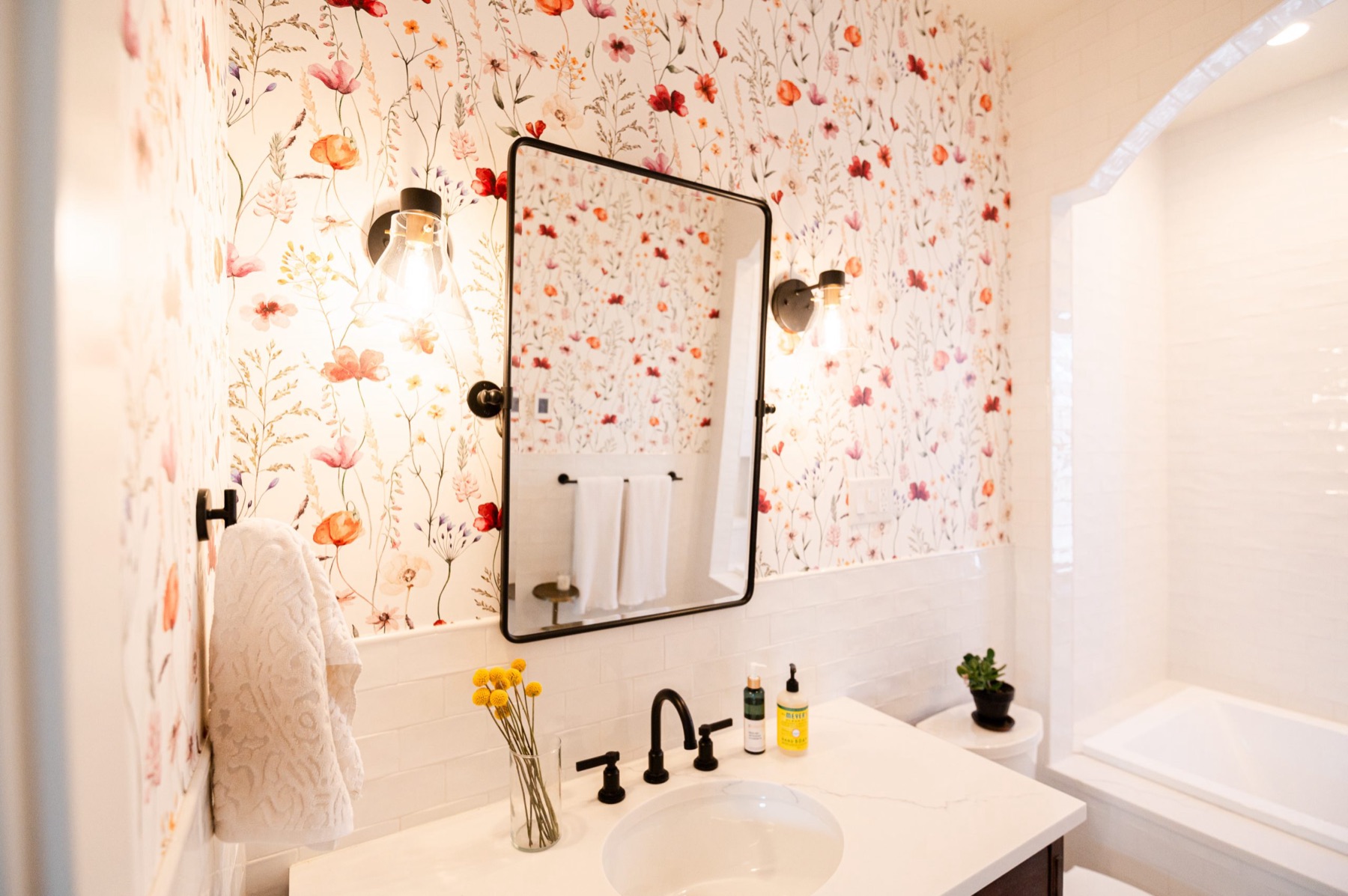 Powder room with floral wallpaper and black framed mirror